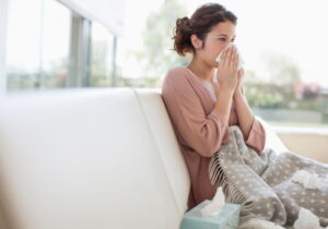 sick-woman-blowing-nose-sitting-on-sofa